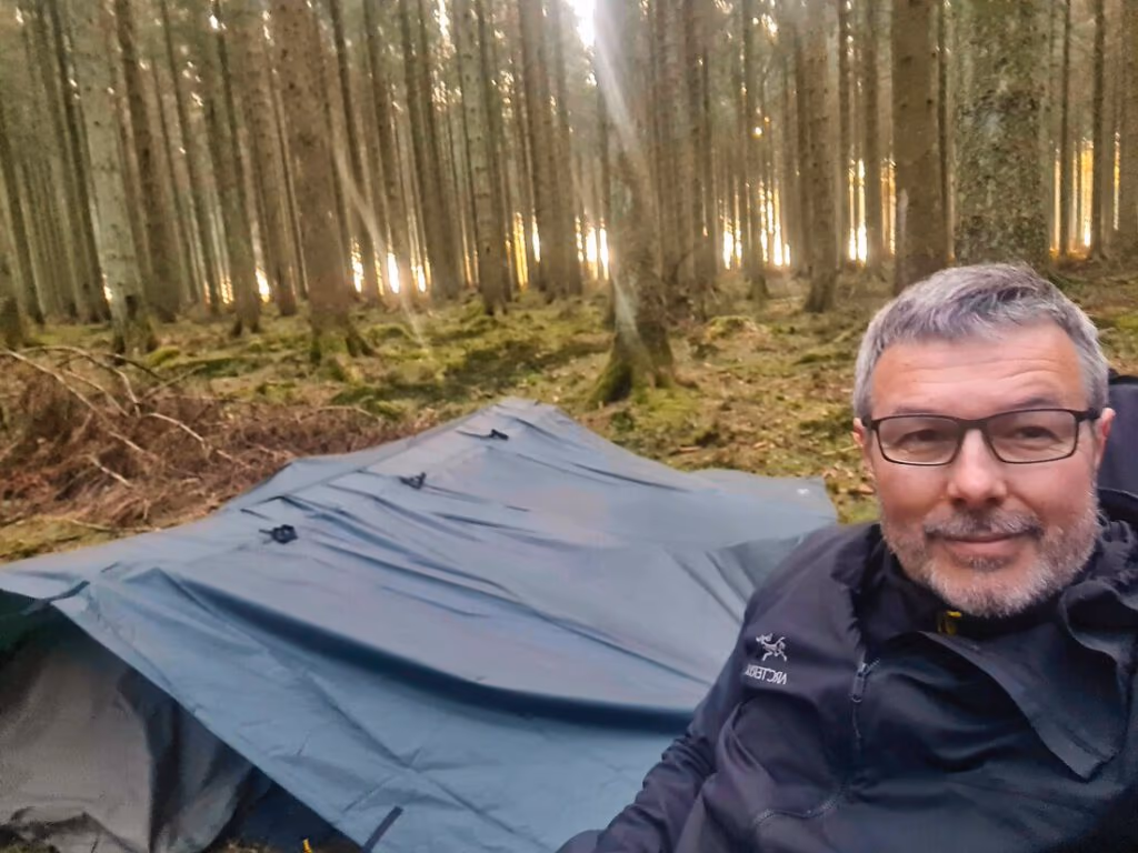 Frank vor seinem niedrigen Tarp im Wald